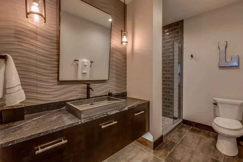 Bathroom with wood flooring, black countertop, sink, faucet, mirror, accent wall, and toilet