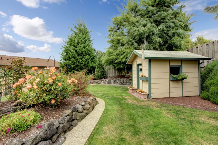 Beautiful backyard with landscaped garden, trees, flowers, wood fences, and an outdoor shed
