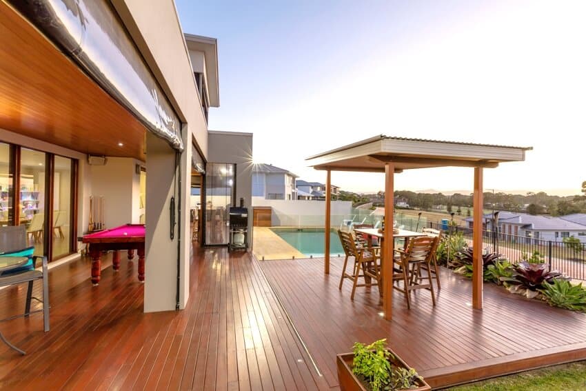 A beautiful backyard wooden deck patio with swimming pool and gazebo