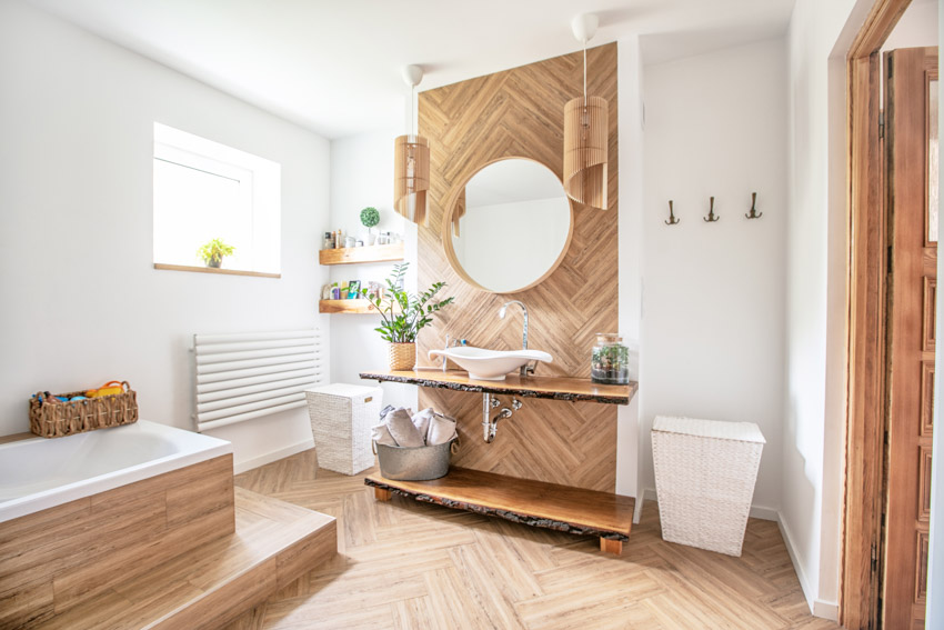Beautiful bathroom with vanity mirror, tub, floating countertop, sink, window, and wood floor