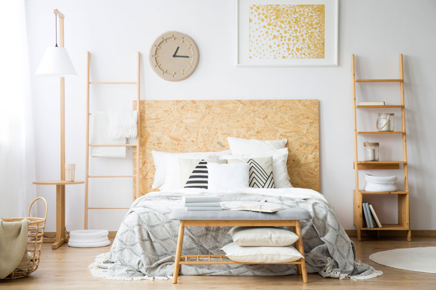Beautiful bedroom with corkboard headboard, ladder nightstands, pillows, comforter, and wall clock