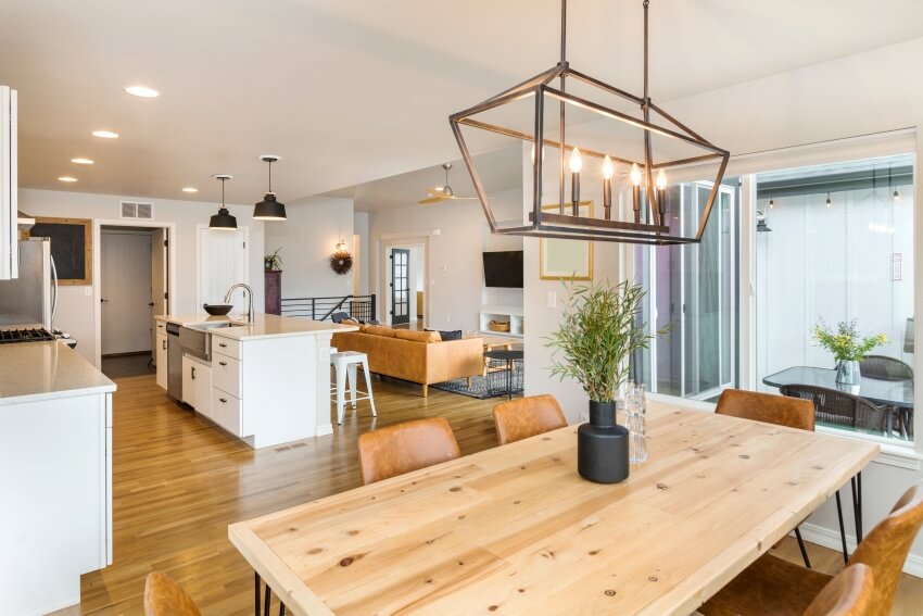 Beautiful farm house kitchen and dining space with modern and industrial fixtures, a large island and wooden floors 