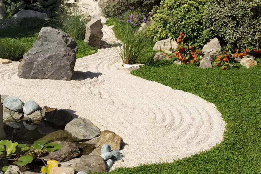 Beautiful landscaped garden with sand, rocks, plants, and flowers