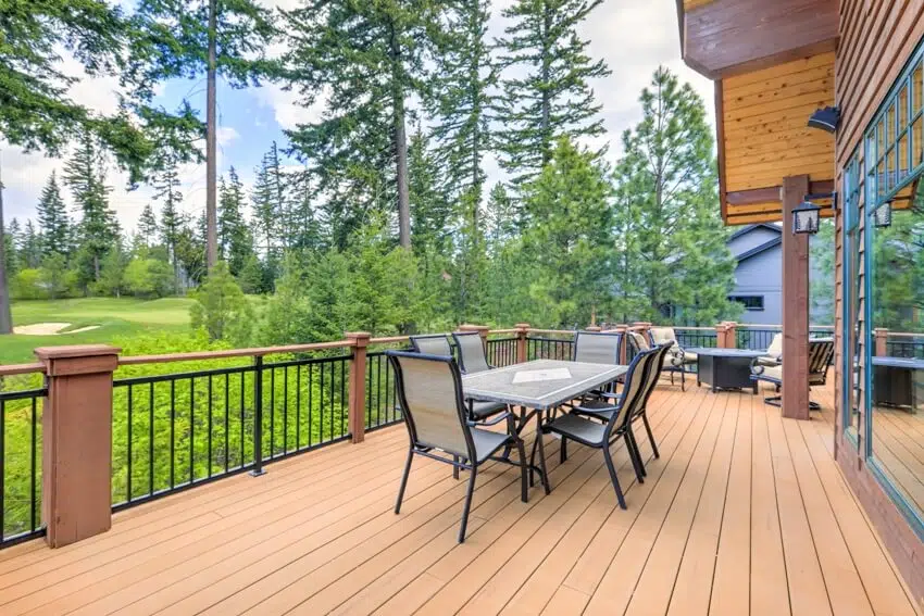 A beautiful large cabin home with chairs and table on wooden deck balcony with overlooking view of golf course