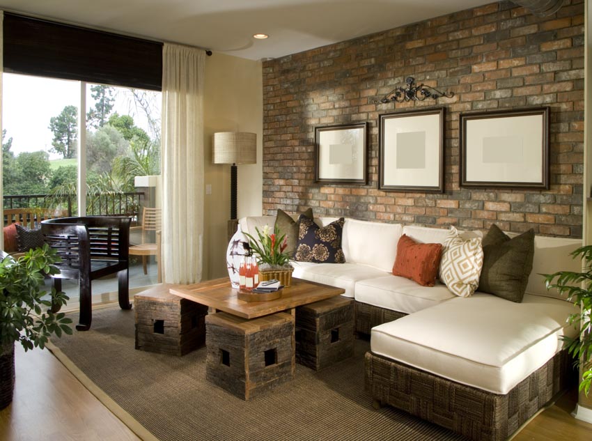 Beautiful living room with wood coffee table, couch, brick wall, floor carpet, lamp, and window curtain