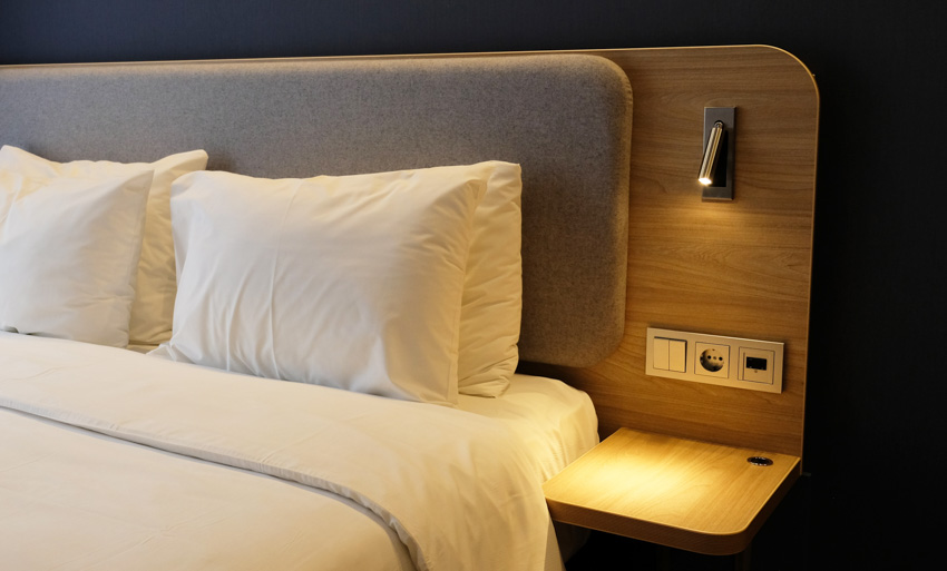 Bed with pillows, comforter, built-in headboard nightstand, mounted light, and charging outlet
