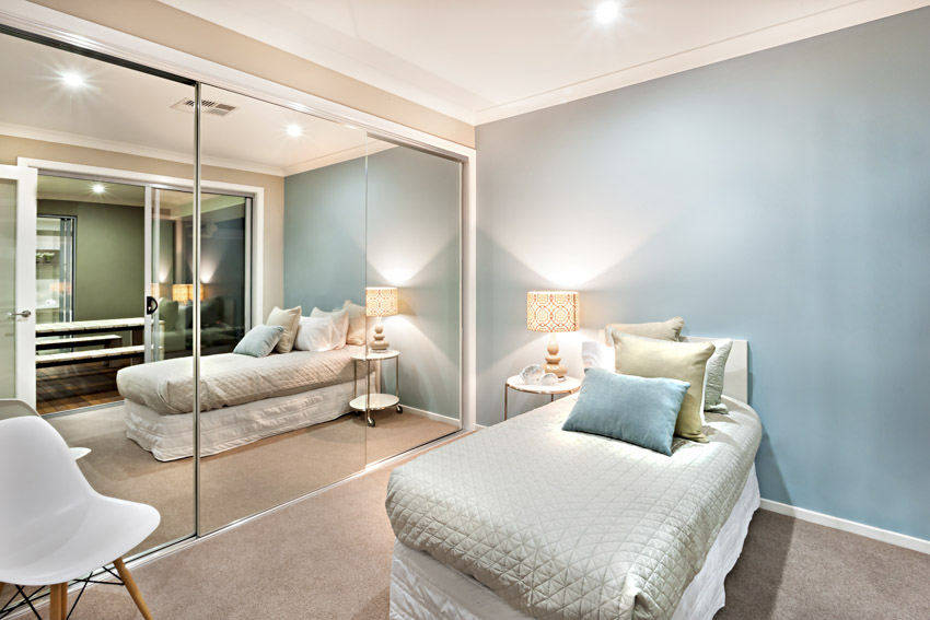 Bedroom with blue wall, bed pillows, chair and mirror