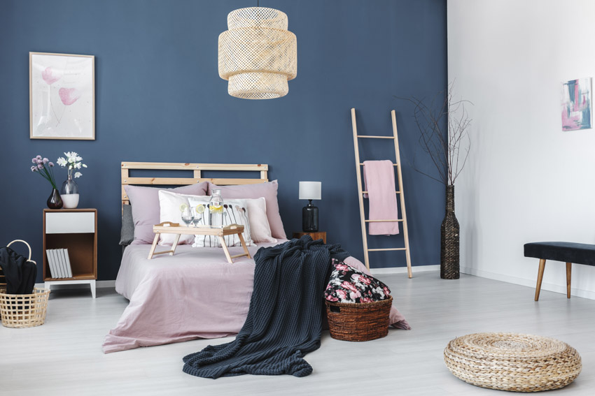 Bedroom with blue walls, pink bedsheets, bookshelf nightstands, and hanging light