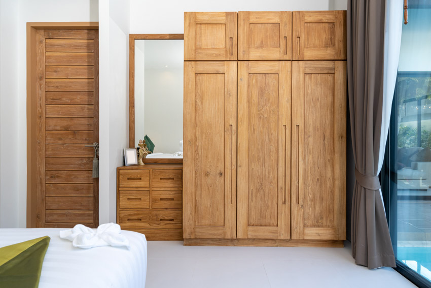 Bedroom with cedar closet, dresser, mirror, door, window, and curtains