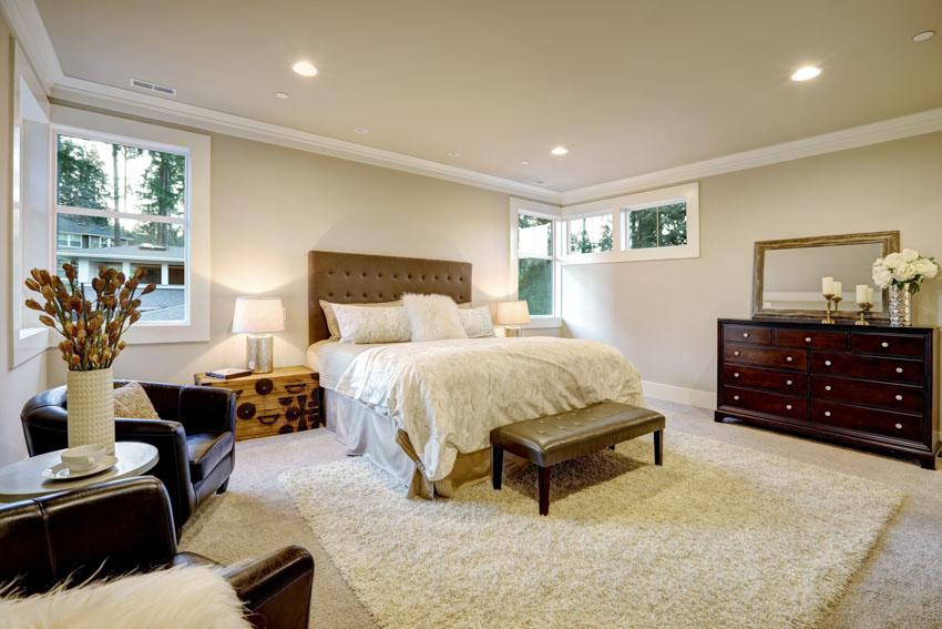 Bedroom with floor rug, headboard, DIY nightstand chest, lamp, windows, dresser, and ceiling lights