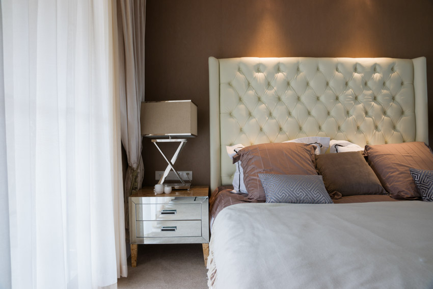 Bedroom with tufted headboard, and chrome nightstand