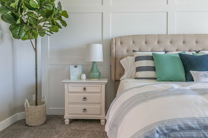 Bedroom with headboard, pillow, comforter, indoor plant, and nightstand