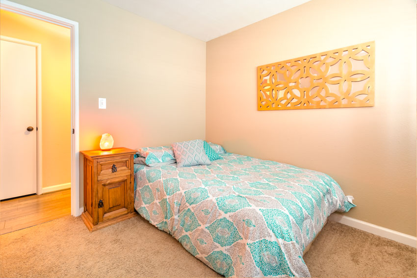 Bedroom with tall nightstand, lamp, pillows, and comforter