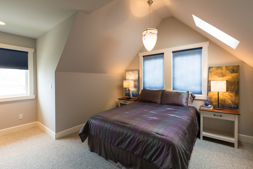 Bedroom with sloping ceiling, carpet flooring, skylight window, lamps, and nightstands