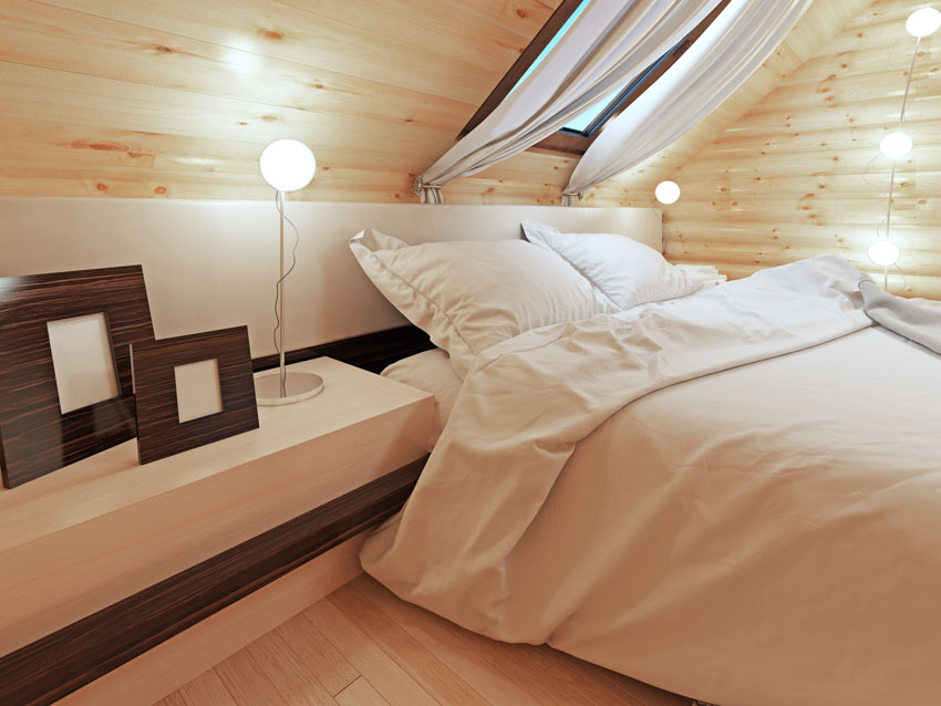 Bedroom with wood sloping ceiling, oversized nightstand, and skylight window