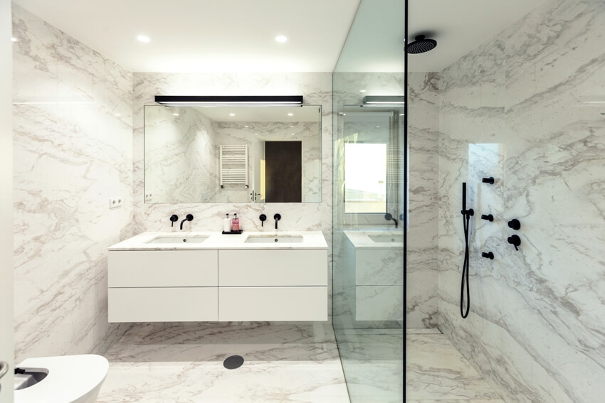 Bookmatched marble bathroom interior design with white countertop and glass shower wall