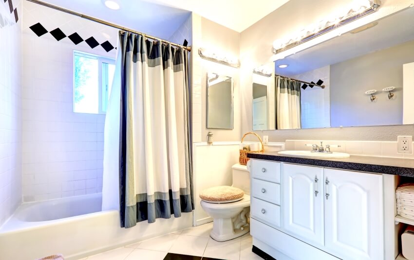 Bright bathroom with white cabinet, tile floor, bathtub, and curtain in an adjustable rod