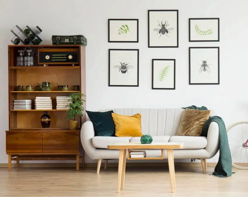 A bright vintage living room interior with bookcase and framed posters above sofa