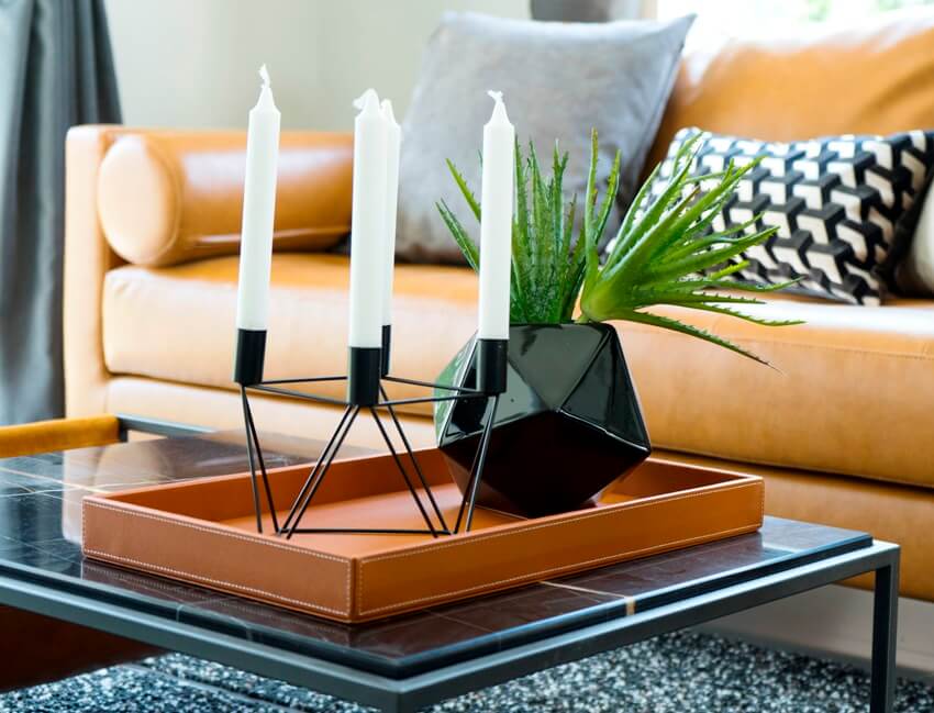 Brown leather sofa near a coffee table with black vase and modern candle holder