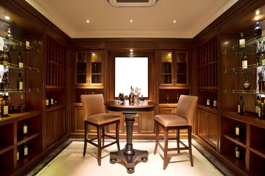 Cellar with wine table, cushioned chairs, wood cabinets, and ceiling lights