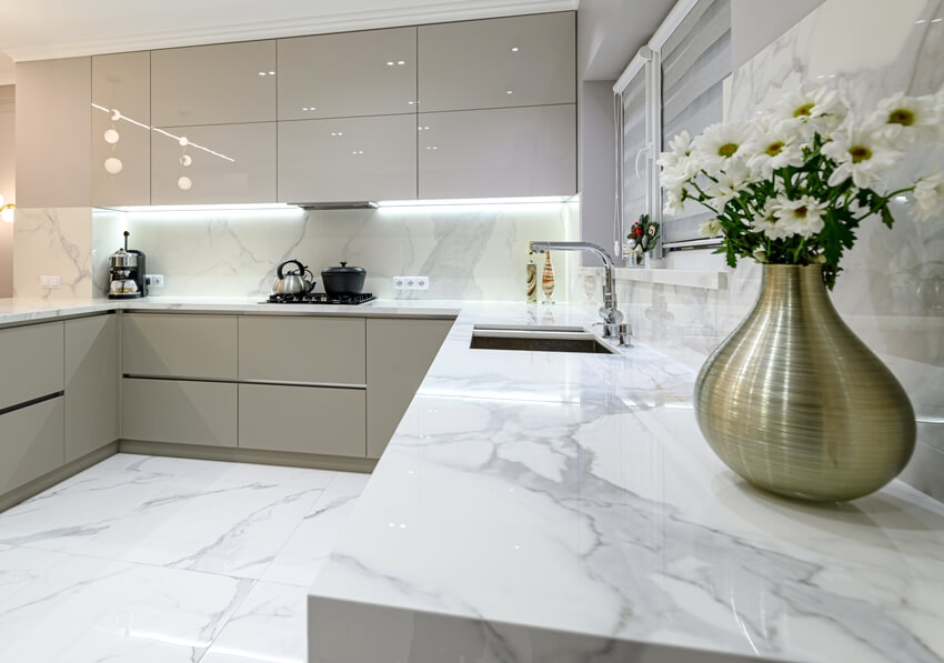Closeup of luxury large modern white statuario marble kitchen with beige cabinets