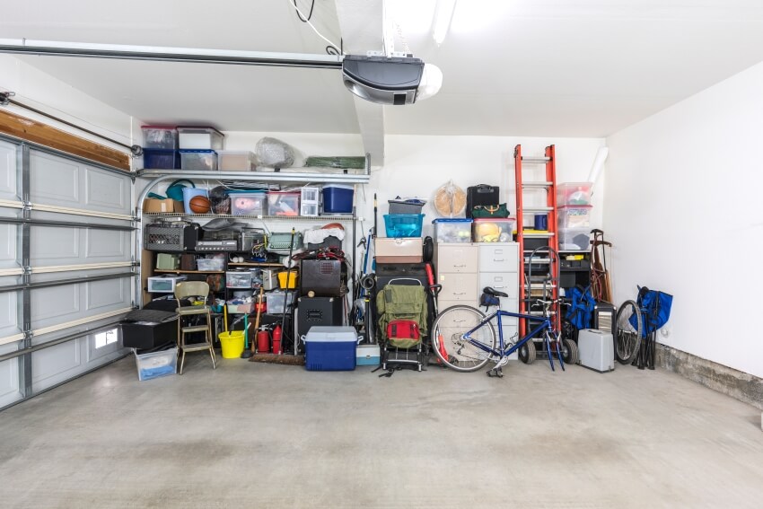 A cluttered but organized clean car garage with file cabinets, boxes and tools