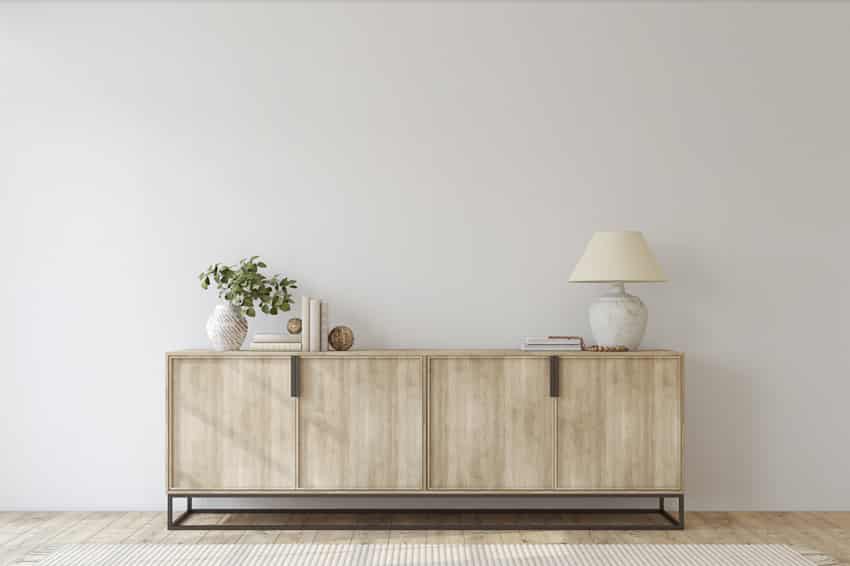 Console table made of wood with a plant, and lamp on it