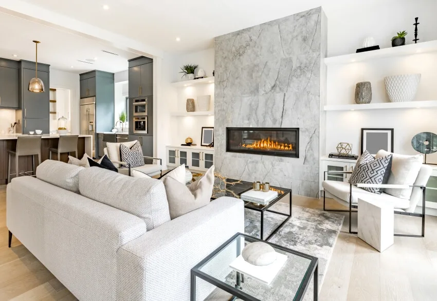 Open concept room with fireplace, side tables with glass tops and upholstered cushions