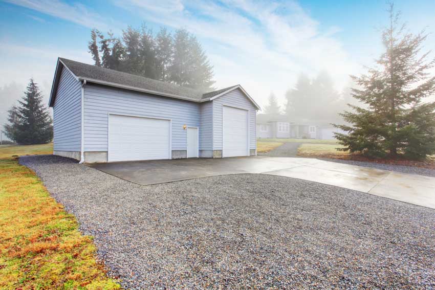 Detached garage with siding, roof, epoxy walkway, and crushed concrete driveway