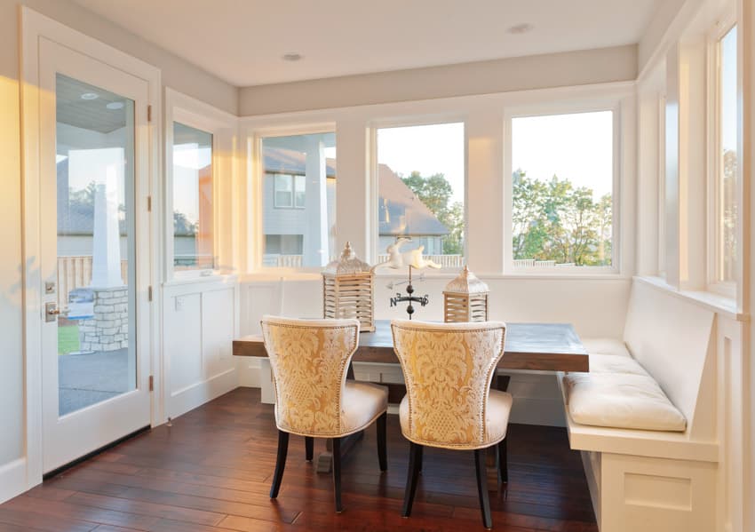 Dining room with wood flooring, table, chairs, nook seating, glass door, and triple pane windows