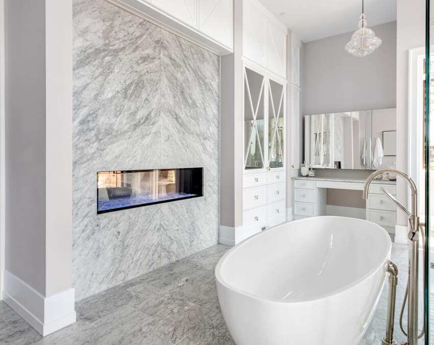 Elegant bathroom with bookmatched marble wall fireplace and bathtub in new luxury home