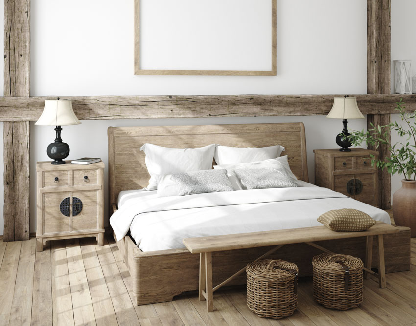 Farmhouse bedroom with wood floor, nightstand, lamps, baskets, wooden beams on the wall, and indoor plant