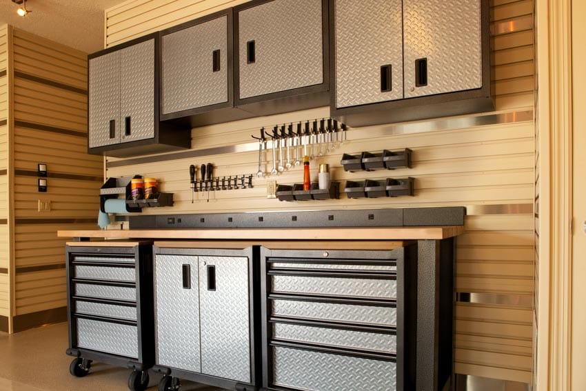 Garage workbench with slatwall storage panel backsplash, cabinets, drawers, and countertops