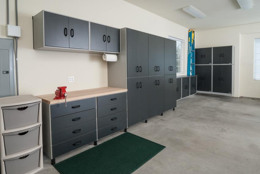Garage workspace with sheetrock backsplash, cabinets, drawers, and concrete floors