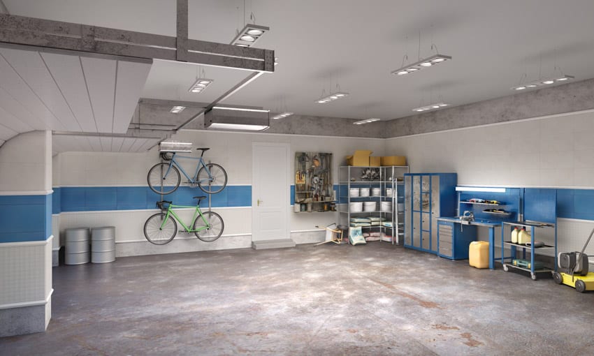 Garage workplace with tile workbench backsplash, ceiling lights, cabinets, and concrete floor