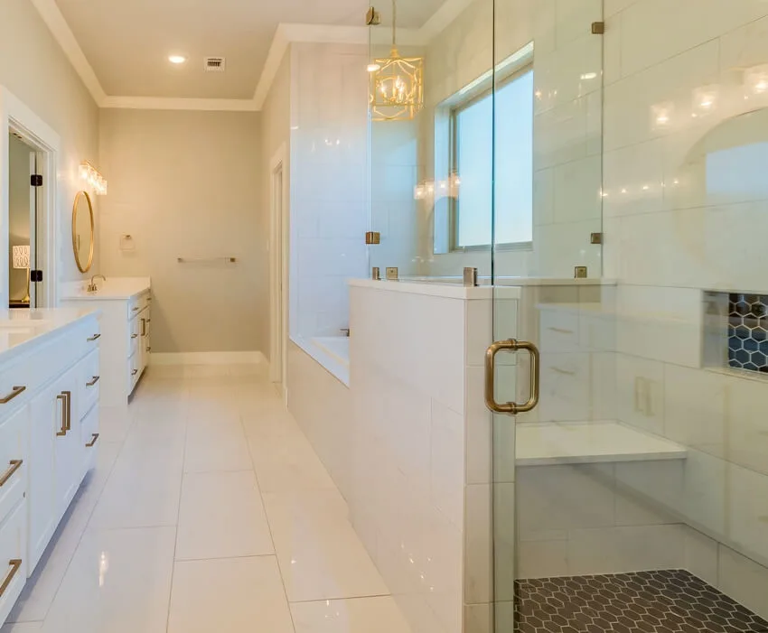 Gorgeous white bathroom with brass accents, a shower with glass doors and a pony wall
