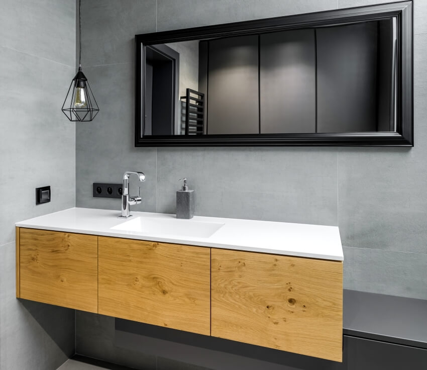 Gray bathroom with white laminate countertop, black mirror and wooden cabinet