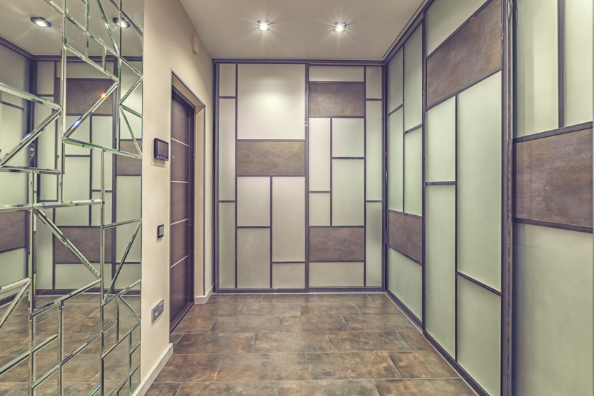 Hallway with beveled mirror wall panel, glass tile walls, door, and ceiling lights
