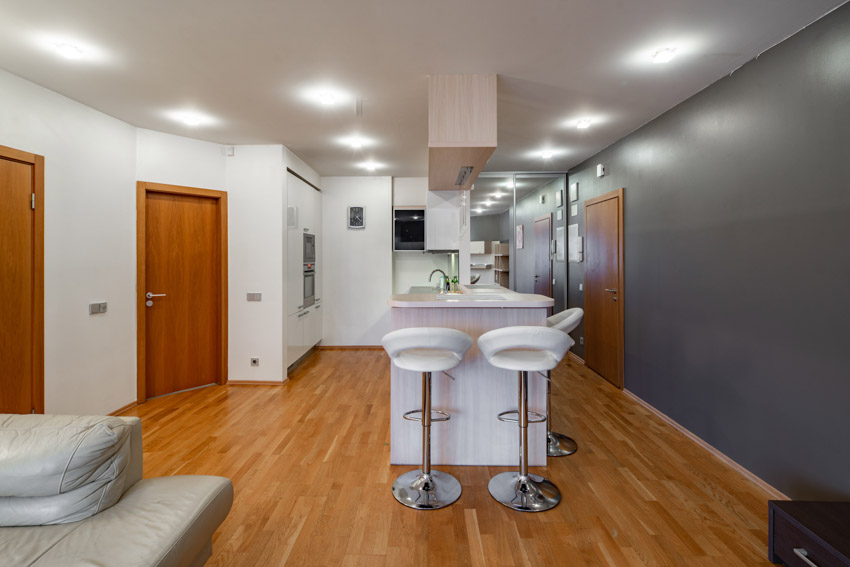 Home bar area with countertop, ceiling lights, and white stools