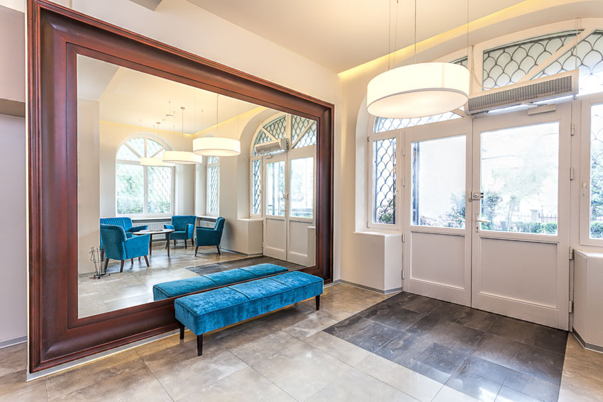 House entrance way with mirror, blue cushioned bench, and white doors