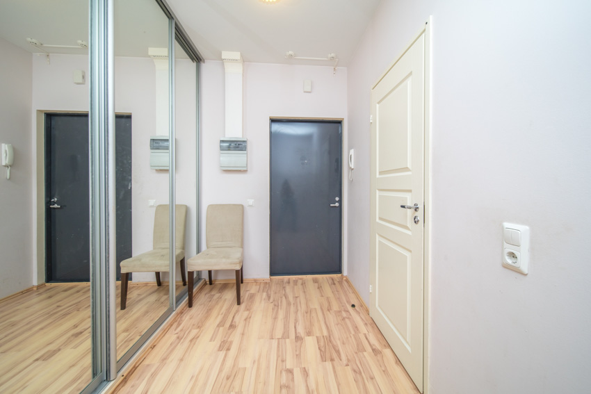 Hallway with doors, white walll on one side and mirror on the other