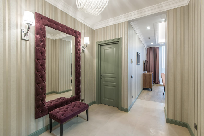 House interior with vertical striped walls, cushioned seat, and decorative mirror