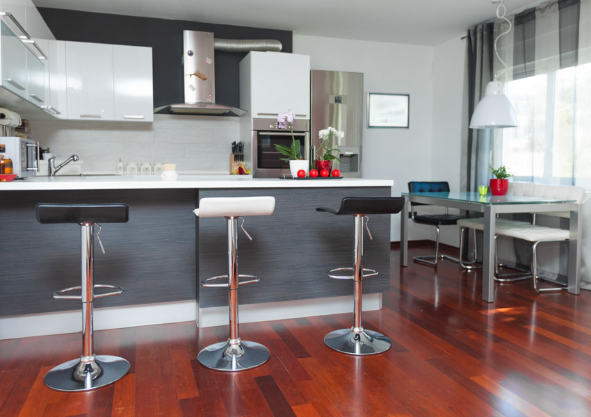 Kitchen bar area with adjustable bar stools, wood floor, backsplash, range hood dining table chairs and windows