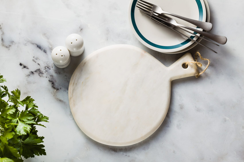 Kitchen countertop with plate, utensils, and a marble cutting board