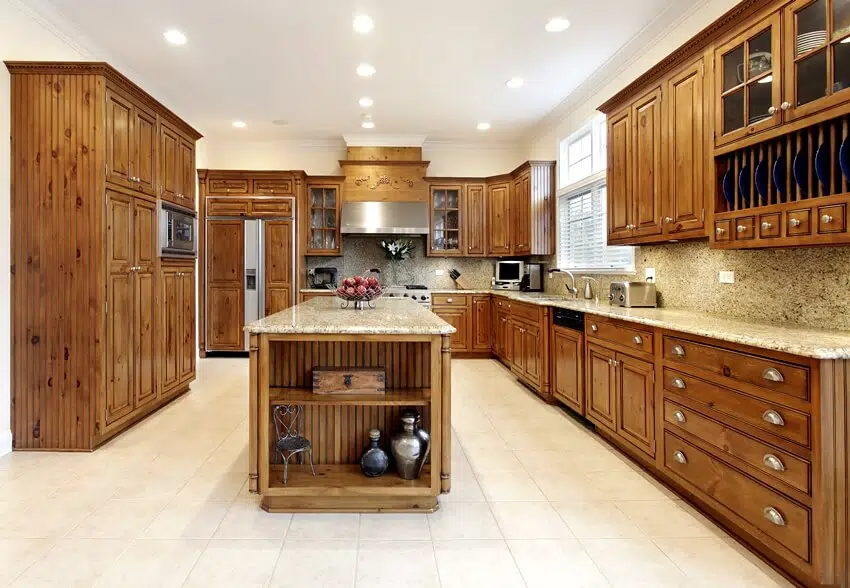 Spacious kitchen in luxury home with granite island, knotty alder cabinets and tiled flooring