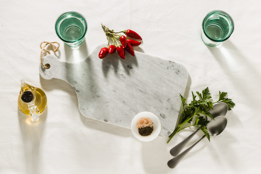 Kitchen surface with glasses, utensils, and marble cutting board on it