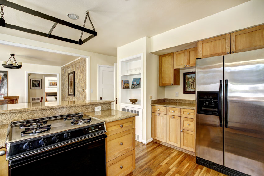 Kitchen with ash cabinets, refrigerator, wood floors, stove, oven, and countertops