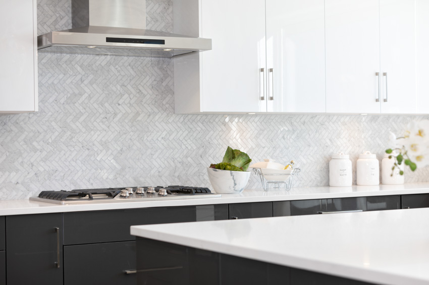 Kitchen with Carrara marble backsplash, countertop, cabinets, stove, and range hood
