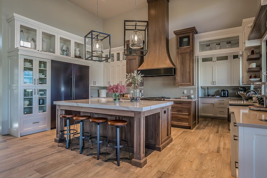 Kitchen with center island, backless bar stools, wood floor, glass cabinets, countertop, and rustic hanging lights