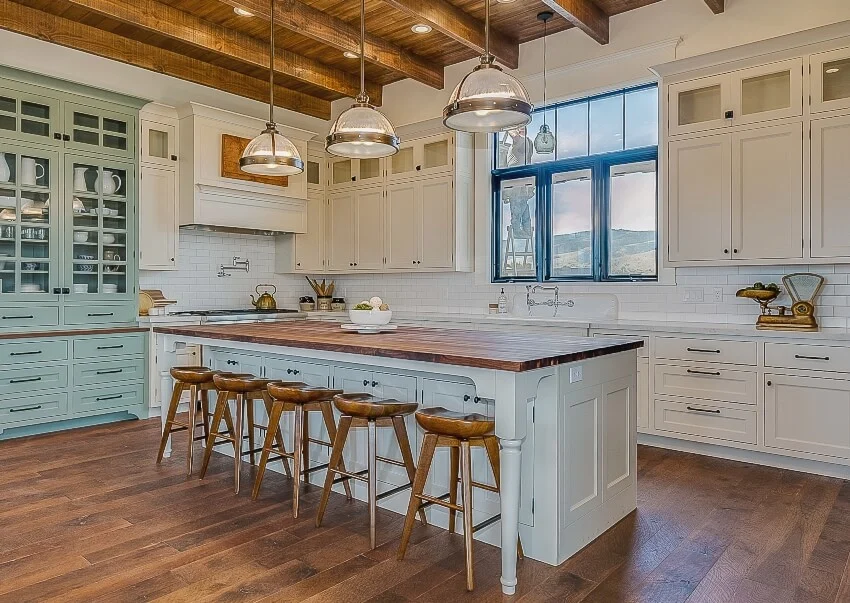 Kitchen with farmhouse design featuring island with ipe wood countertop, wooden chairs and floors